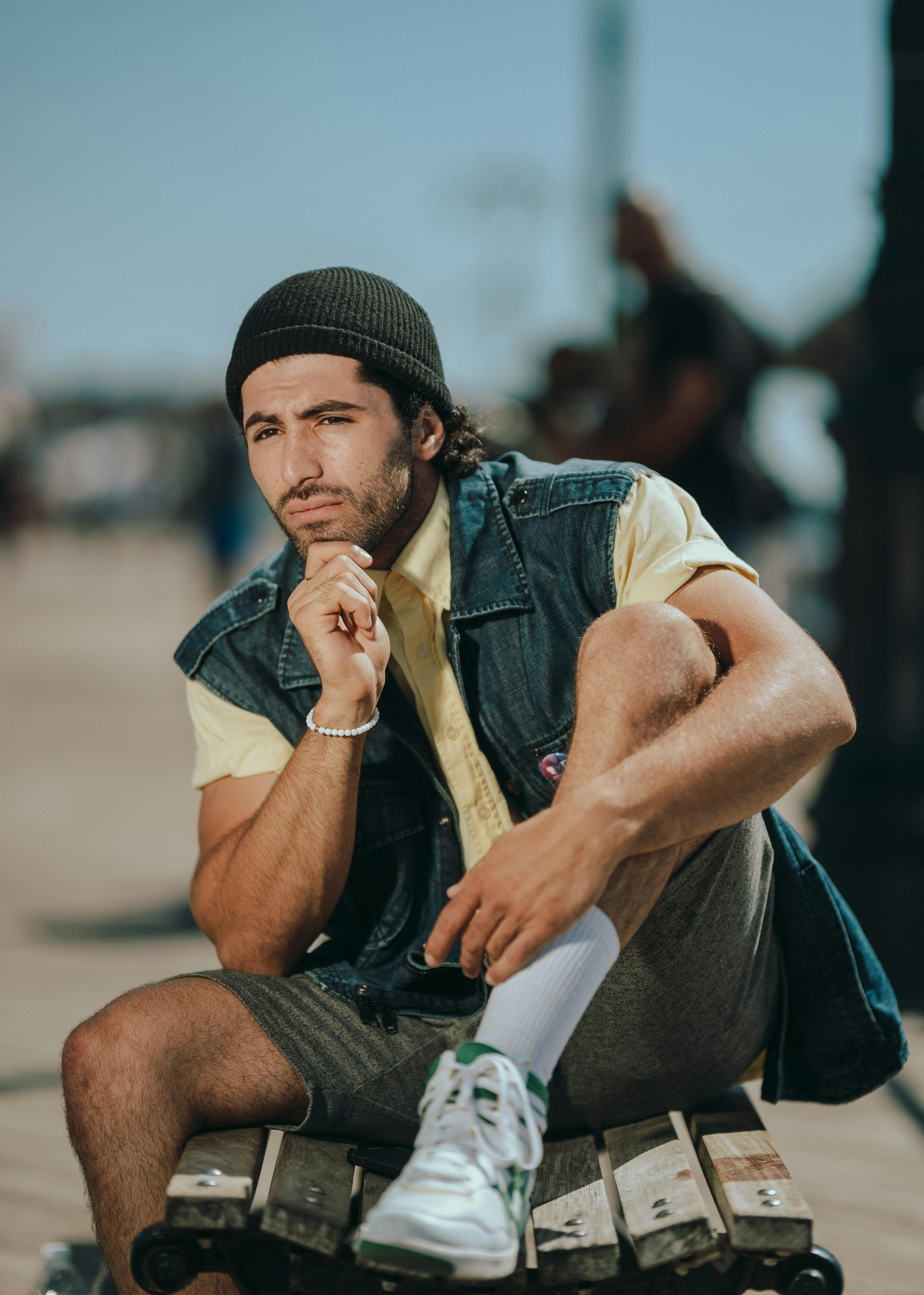 一位时尚男模特坐在纽约的户外，在明媚的阳光下展示休闲时尚