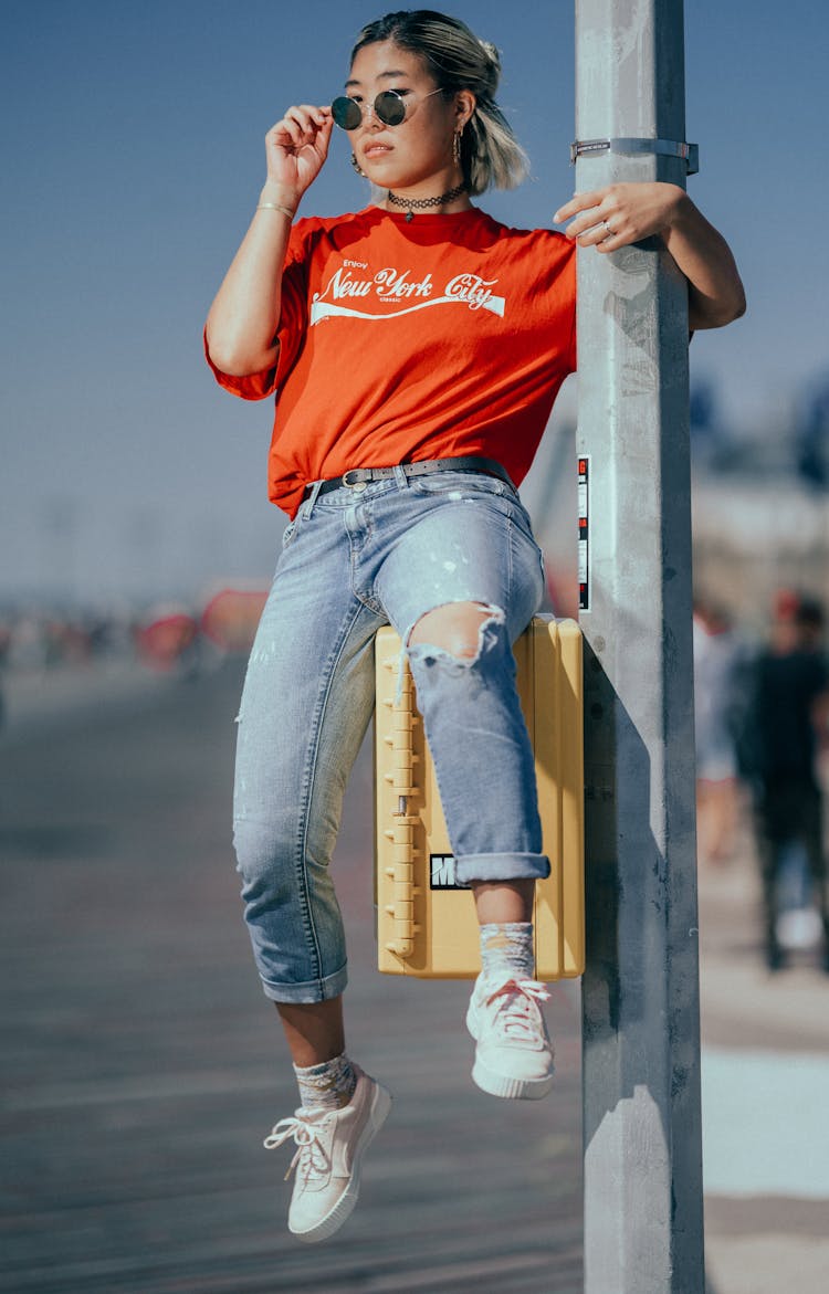 Woman Sitting On Yellow Box Attached On Post