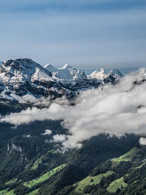 Free Scenic mountain range with snowy peaks and lush green valleys under a clear sky. Stock Photo