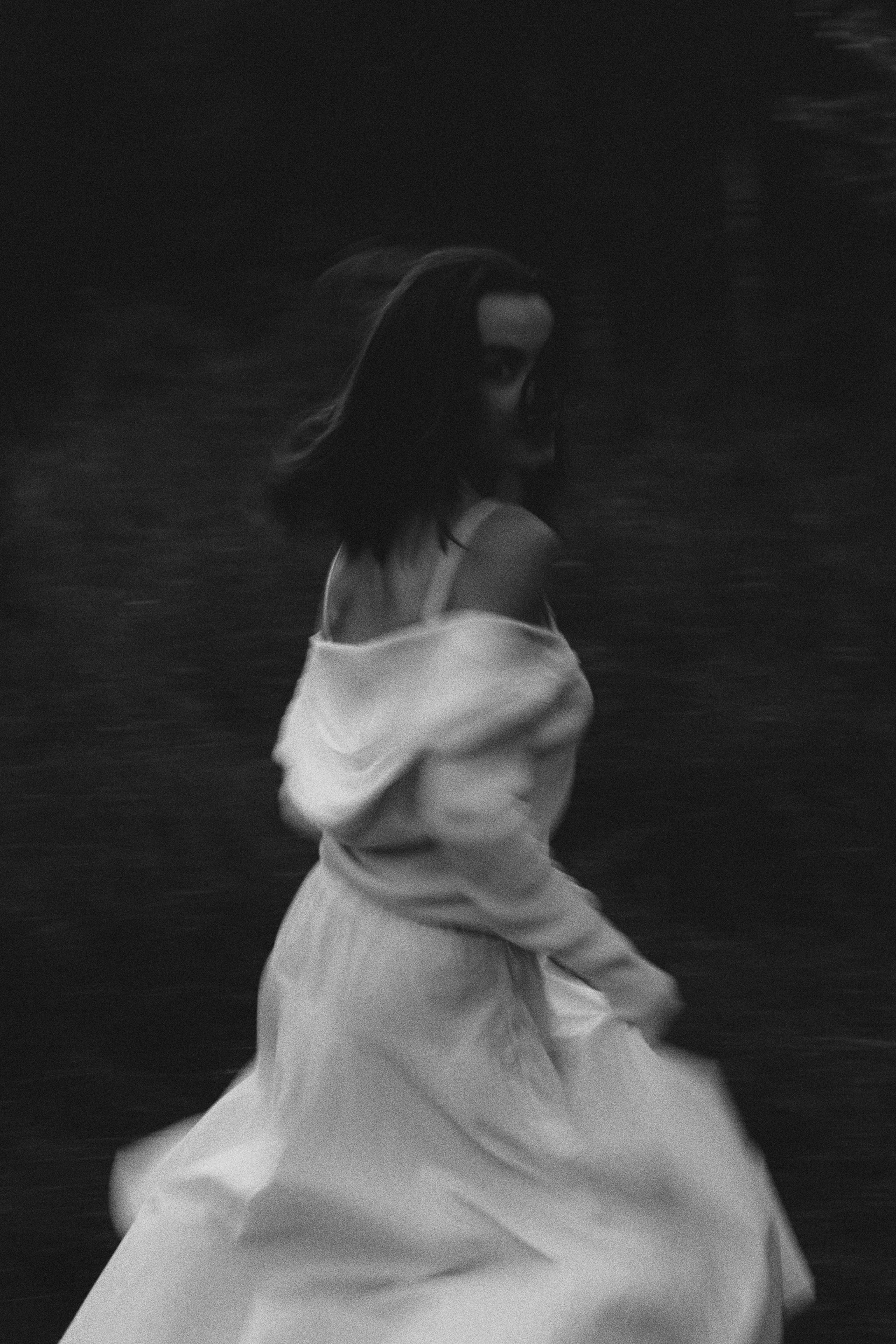Black and white artistic portrait of a woman in motion, creating a blurry effect.