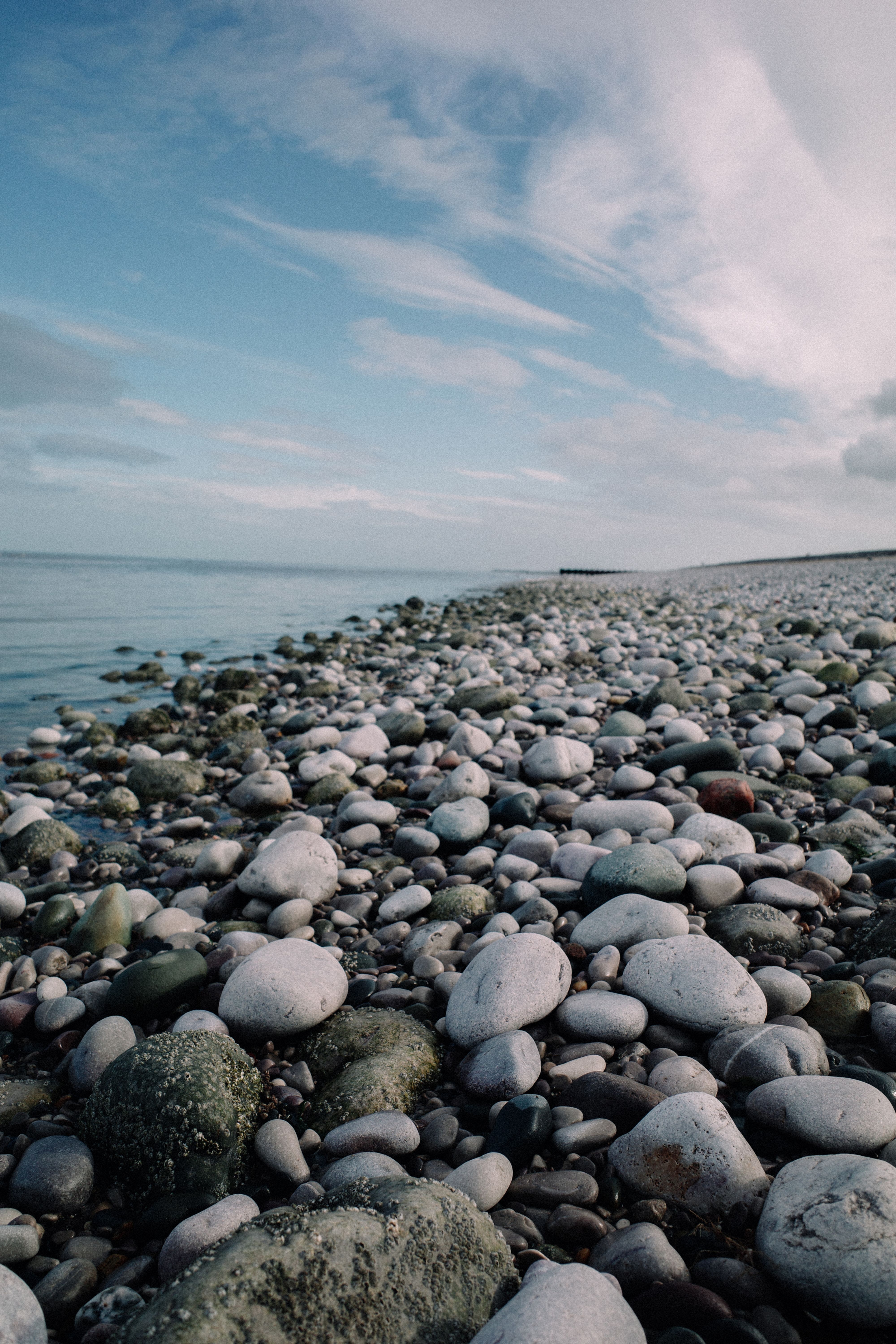 Gratis Serene Pebble Beach Seascape Under Blue Sky Lagerfoto