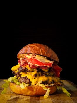 Mouthwatering gourmet cheeseburger with bacon, cheese, and lettuce on a wooden board.