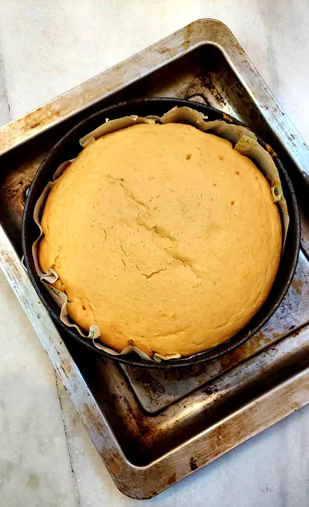 How to Bake Without Eggs: 8 Substitutes That Work for Indian Bakers (2026) 1 A freshly baked golden eggless cake resting in a round tin on a metal baking tray, representing a successful eggless bake.
