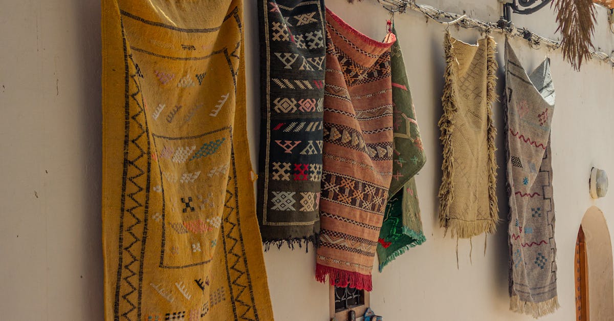 Colorful traditional rugs hung on a wall, showcasing intricate patterns.
