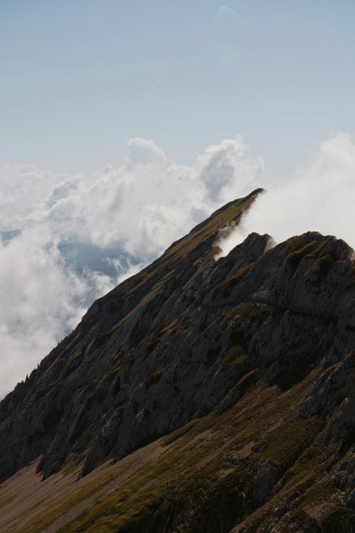 Free Mountain peaks emerging through clouds, offering a stunning natural view. Stock Photo