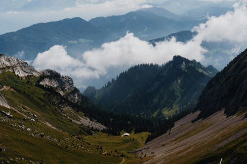 Free Serene alpine mountain landscape with clouds drifting over lush valleys. Stock Photo