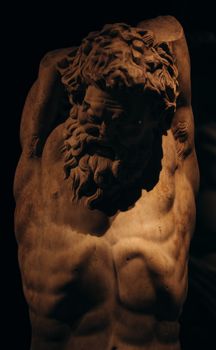 Capture of an ancient Greek male statue with dramatic shadows highlighting details.