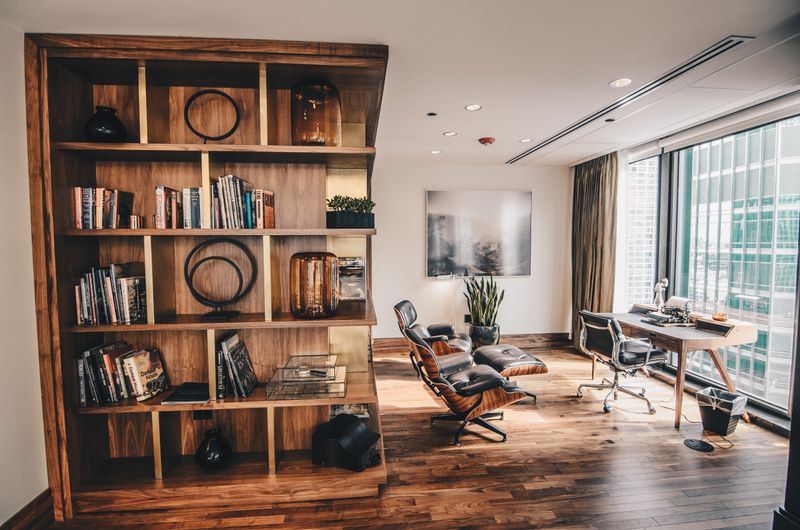 tall bookshelf styled with books and objects in visual thirds behind desk