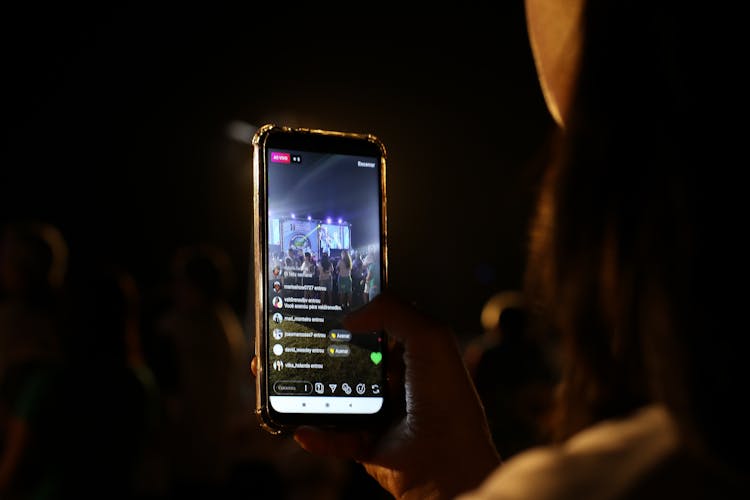 Close-Up Photo Of A Person Recording A Live Performance With Her Cell Phone