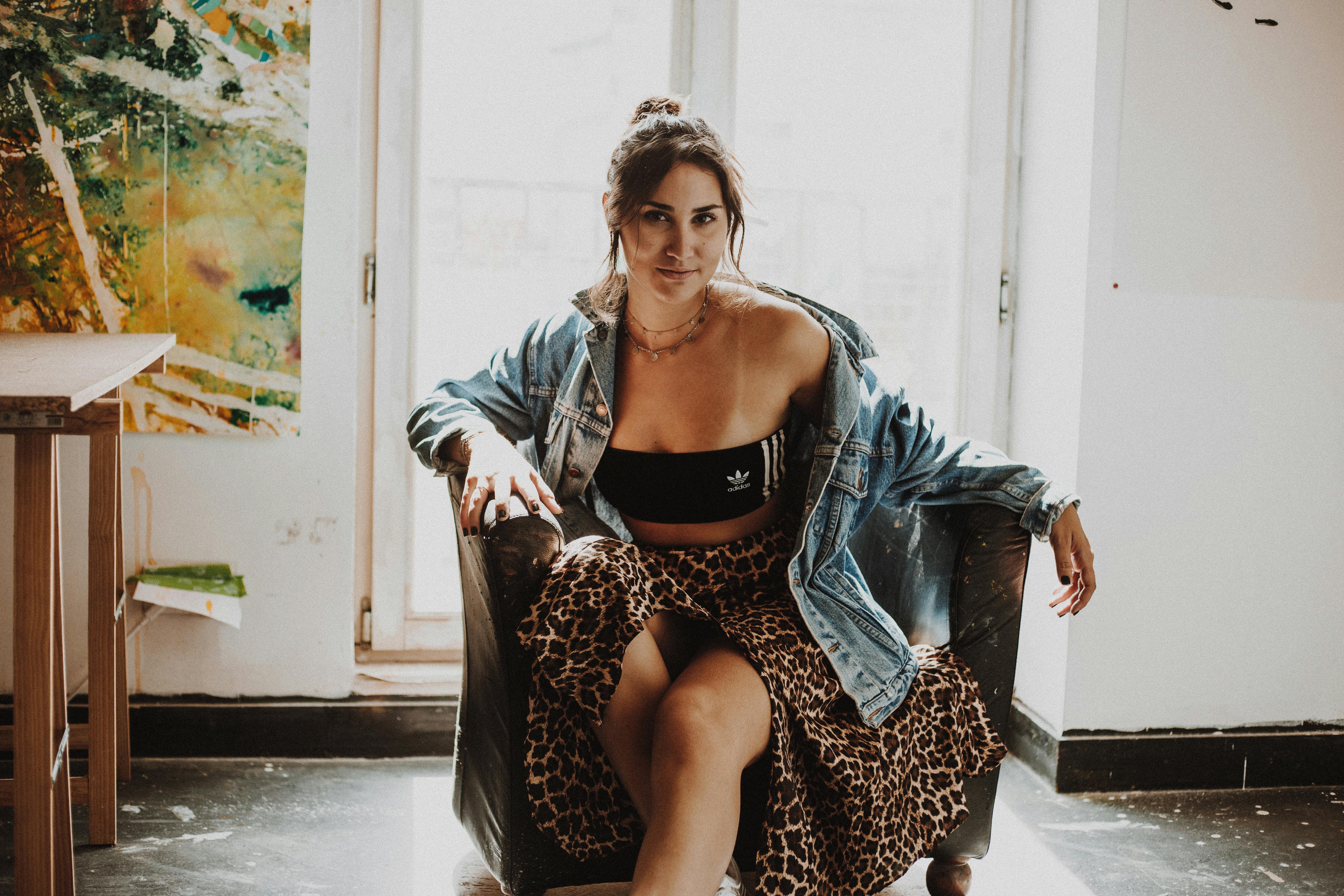 室内，一位穿着牛仔夹克的时尚女士坐在自然光投射出的温暖光芒中