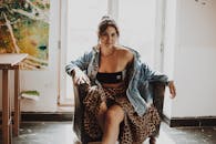 一位穿着牛仔夹克的时尚女性坐在室内，自然光投射温暖