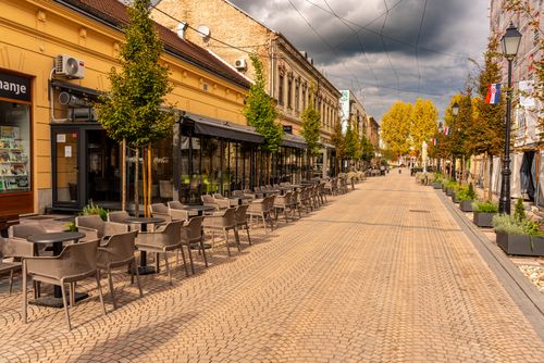 Free Empty European street with cafes and autumn trees under cloudy skies. Stock Photo