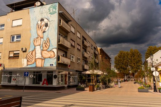 Street view of urban street art on building with dramatic clouds above.