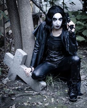 Dark gothic cosplay with horror makeup in a spooky graveyard setting.