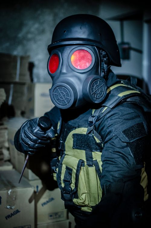 Free Person in tactical gear with gas mask in dimly lit, mysterious environment. Stock Photo