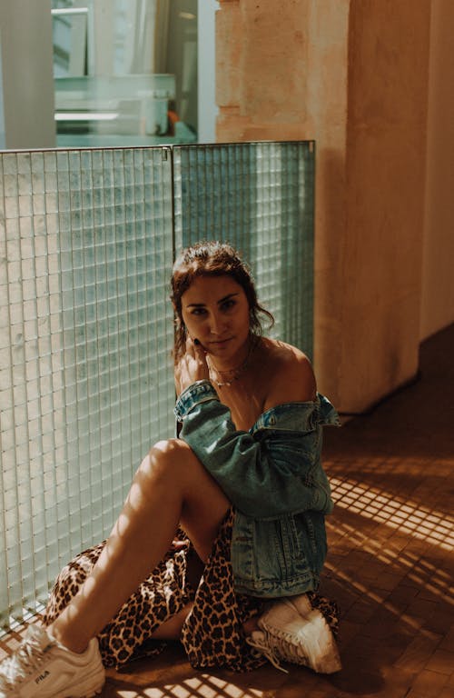 무료 유리 벽 근처에 앉아있는 여자의 사진 스톡 사진