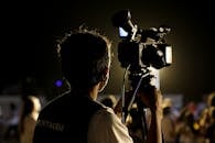 摄影师在夜间使用专业设备拍摄户外活动，捕捉到了充满活力的气氛