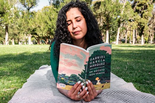 Woman enjoying a book by Gabriel Garcia Marquez in a sunny park.