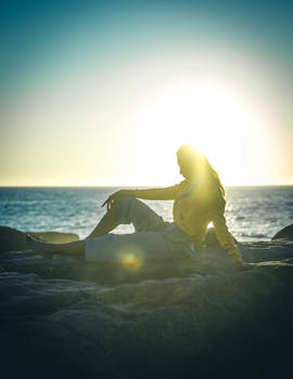 日落时分，金色的阳光洒在海滩上，映出一名女子放松身心的优雅轮廓