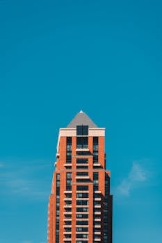 Tall modern brick building with blue sky background, showcasing urban architecture.