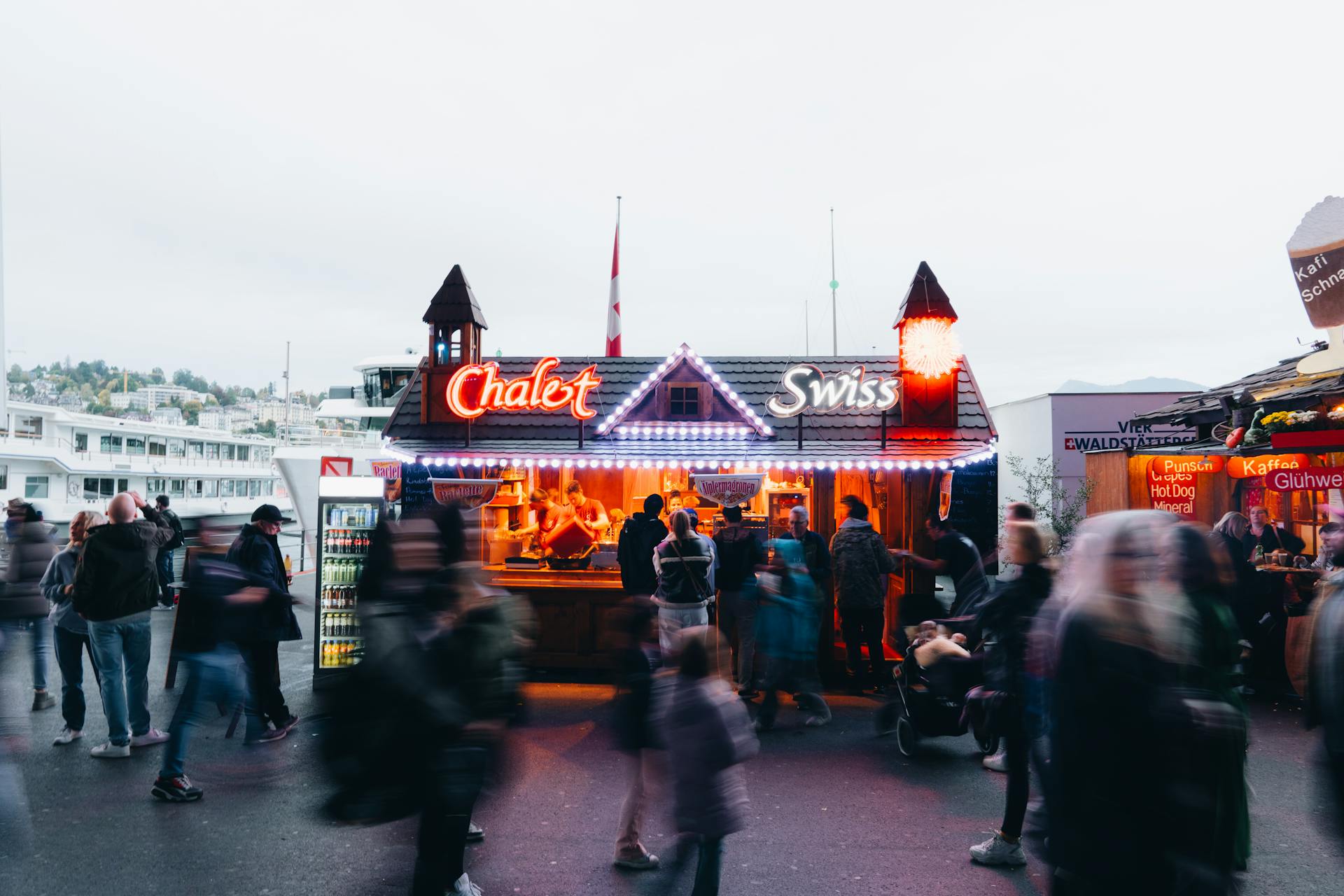 Crowd gathers around Swiss Chalet food stall in an outdoor market scene.