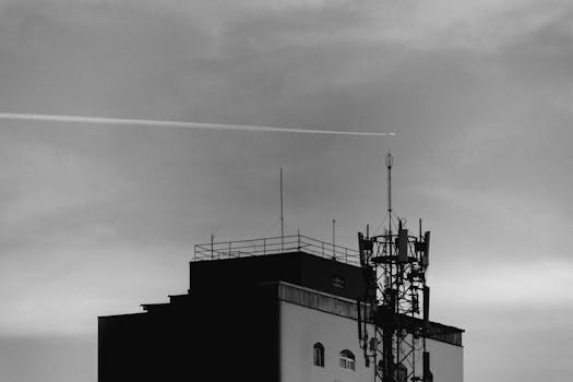 一张黑白照片，拍摄的是夜空中一座带有通信天线的建筑物
