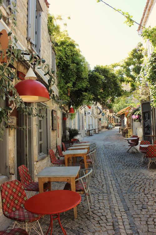 Free Picturesque outdoor café on a European cobblestone street with lush greenery. Stock Photo