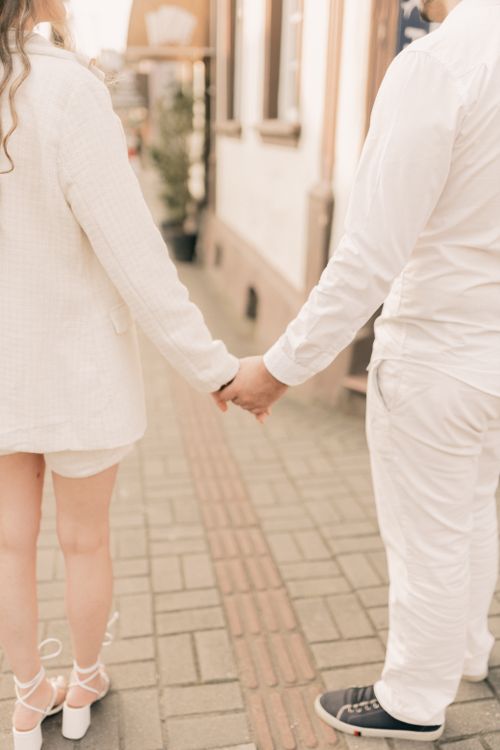 Free Back view of couple holding hands, walking on street in soft focus. Stock Photo