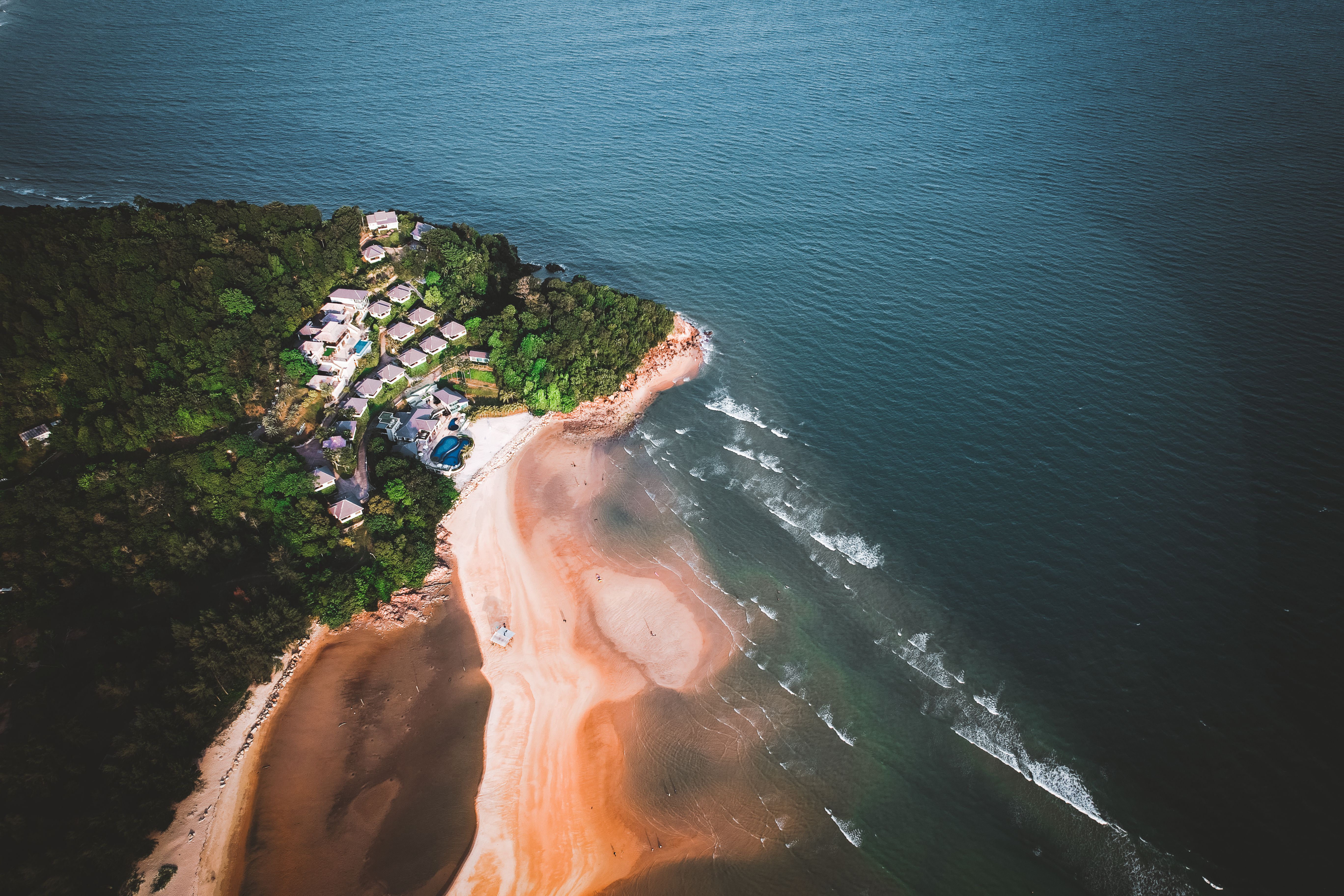 Aerial shot of a serene seaside resort nestled on a lush peninsula surrounded by the ocean.