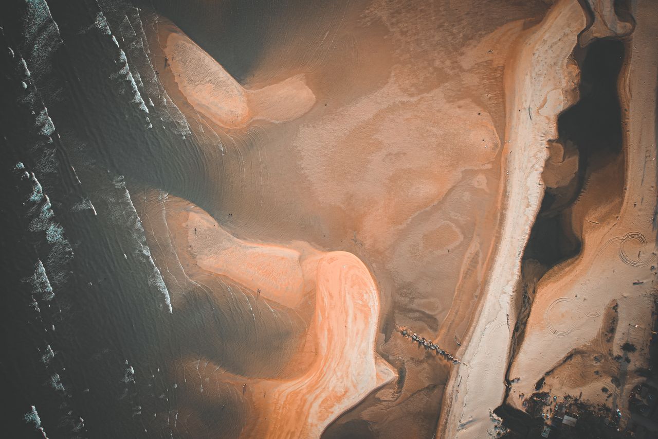 a stunning aerial shot of intricate beach sand patterns and ocean wave
