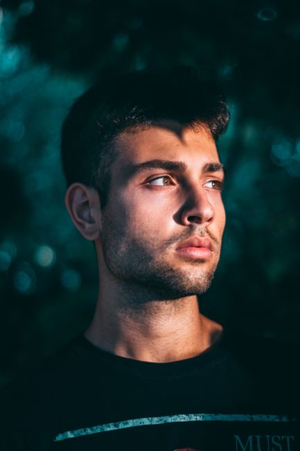 A handsome man posing outdoors with natural lighting in Italy, showcasing modern fashion.