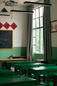 Classic empty classroom with green desks and vintage decor, evoking educational nostalgia.