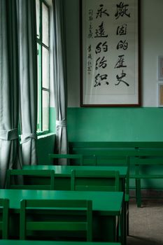 Empty green classroom with Chinese calligraphy and natural light.