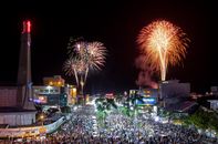 A spectacular night-time fireworks display over a bustling crowd in Long Xuyên city.