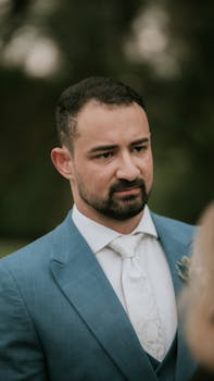 Close-up portrait of a man in a blue suit attending an outdoor event, conveying a sense of elegance and sophistication.