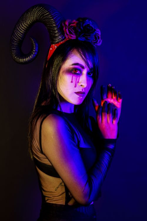 Free Vibrant portrait of a woman with horned headpiece and creative makeup in moody lighting. Stock Photo