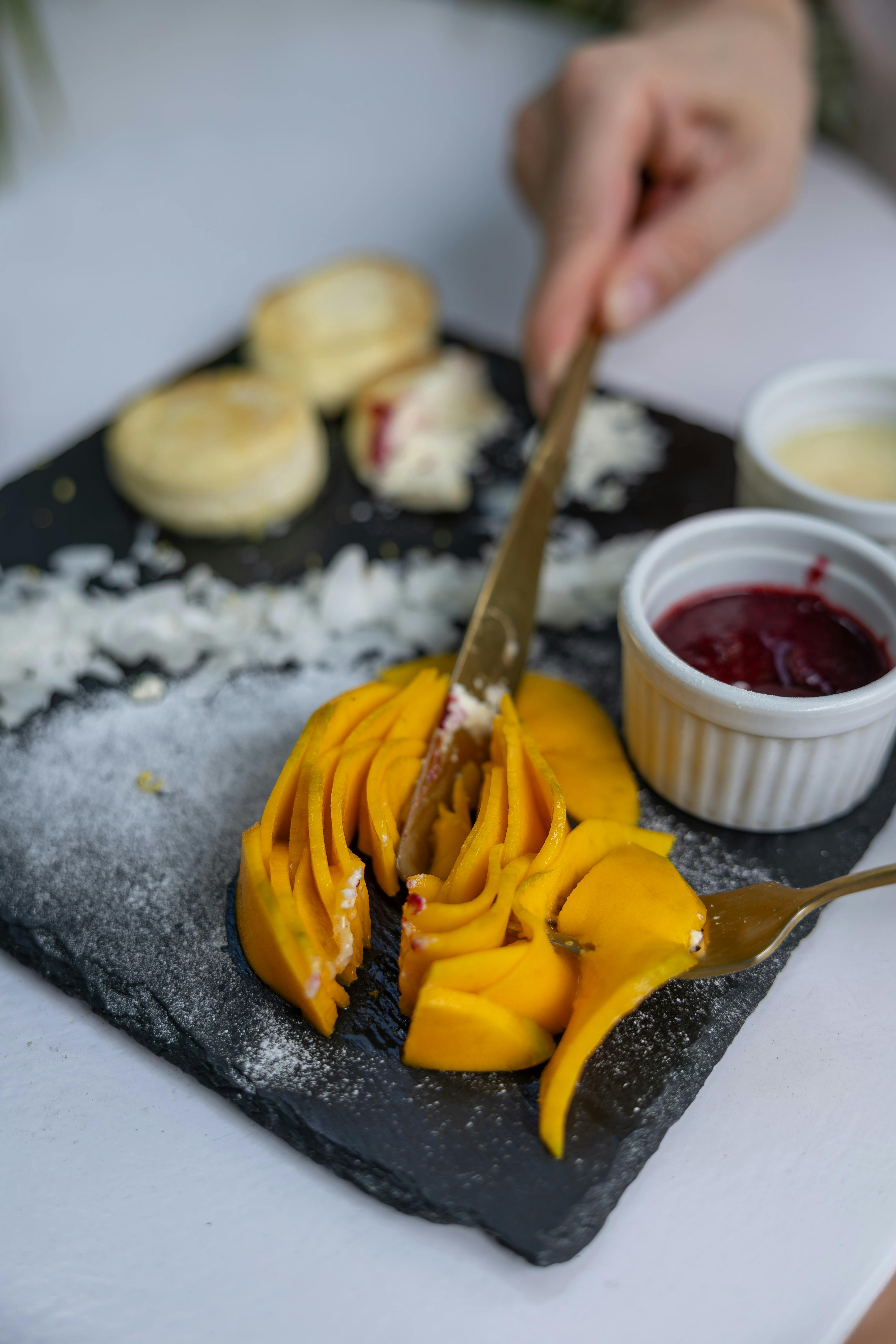 A vibrant serving of sliced mangoes and jam on a slate platter, ready to enjoy.