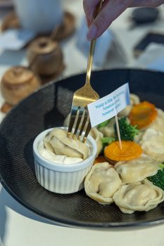 A delicious plate of dumplings served with vegetables and sour cream on a stylish dish.