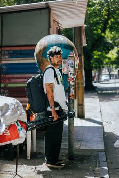 Man standing on city street with backpack and tripod, ready for adventure.