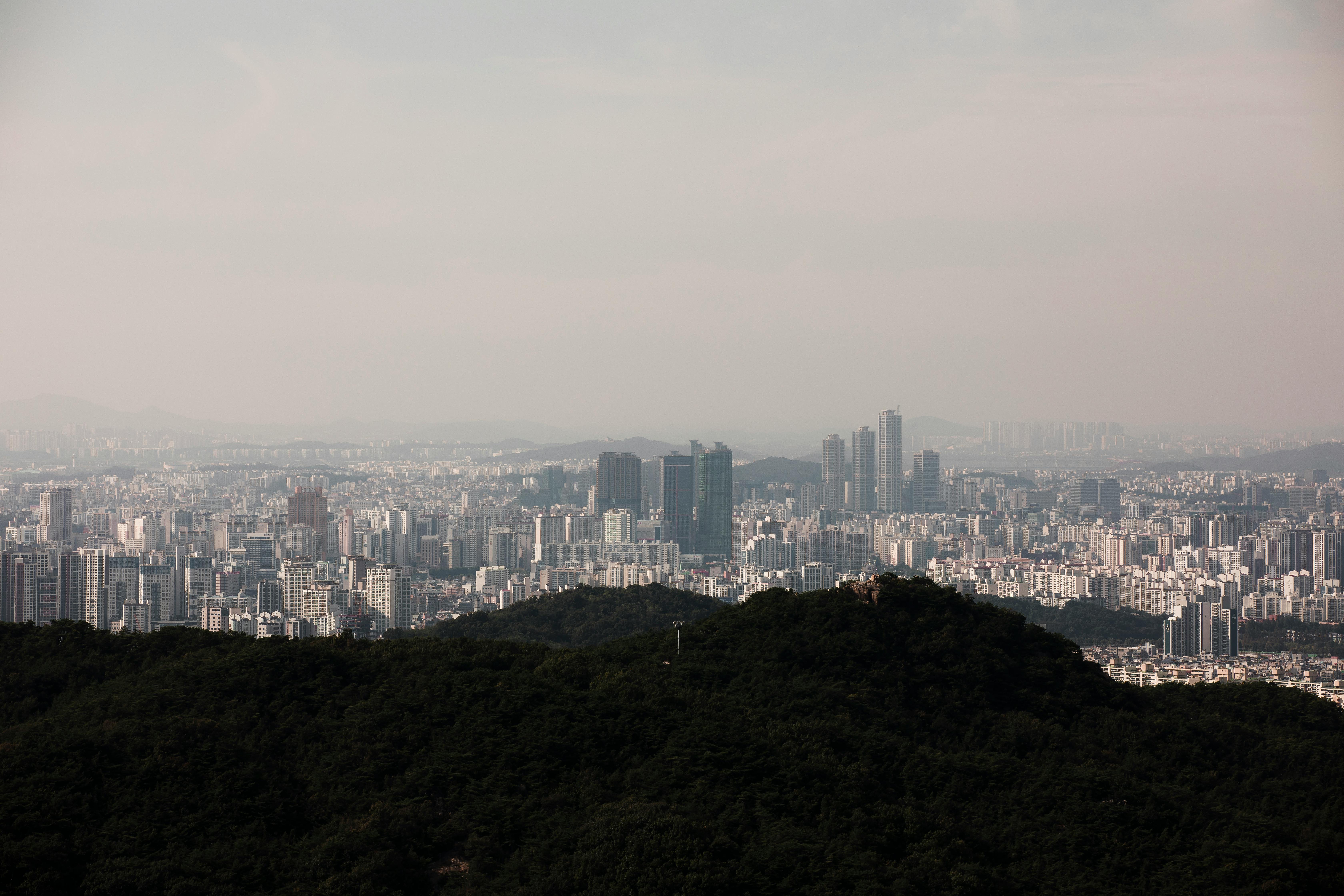Aerial view of a vast city skyline with foreground hills, showcasing urban density.