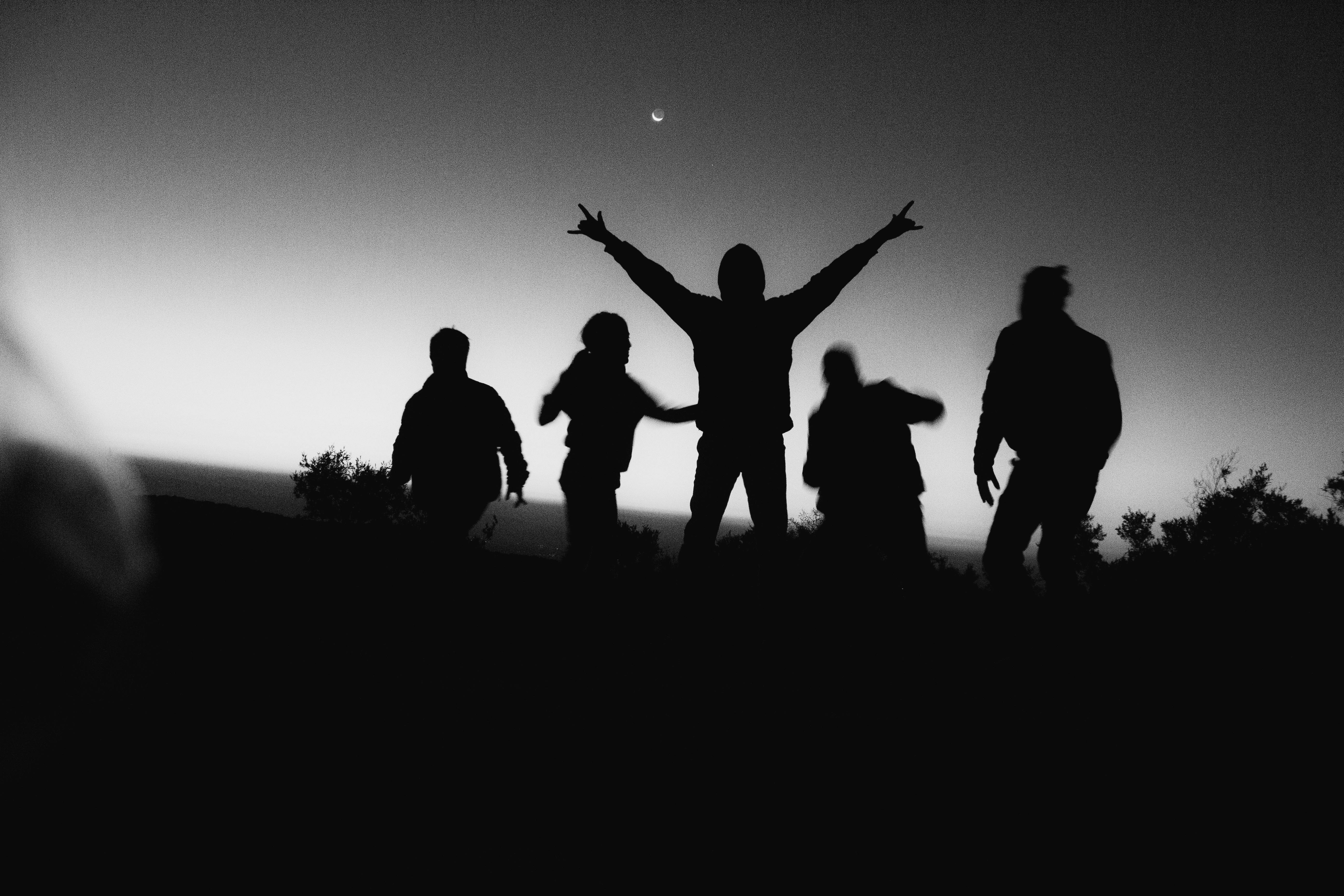 Silhouetted people celebrating under a crescent moon during dawn in Tochimilco, Mexico.