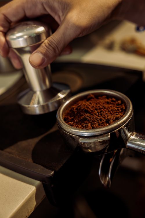 Free Close-up of a barista tamping ground coffee into a portafilter, ready for espresso making. Stock Photo