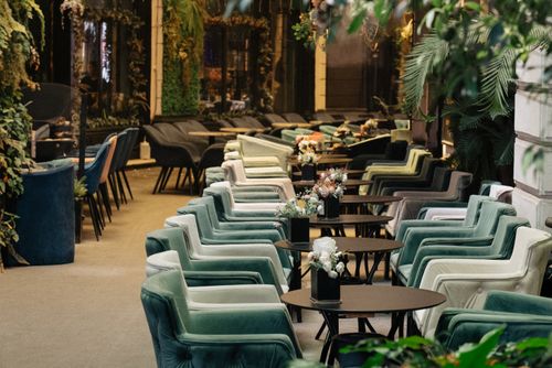 Free Chic café with colorful armchairs and greenery offering a relaxing outdoor dining experience. Stock Photo