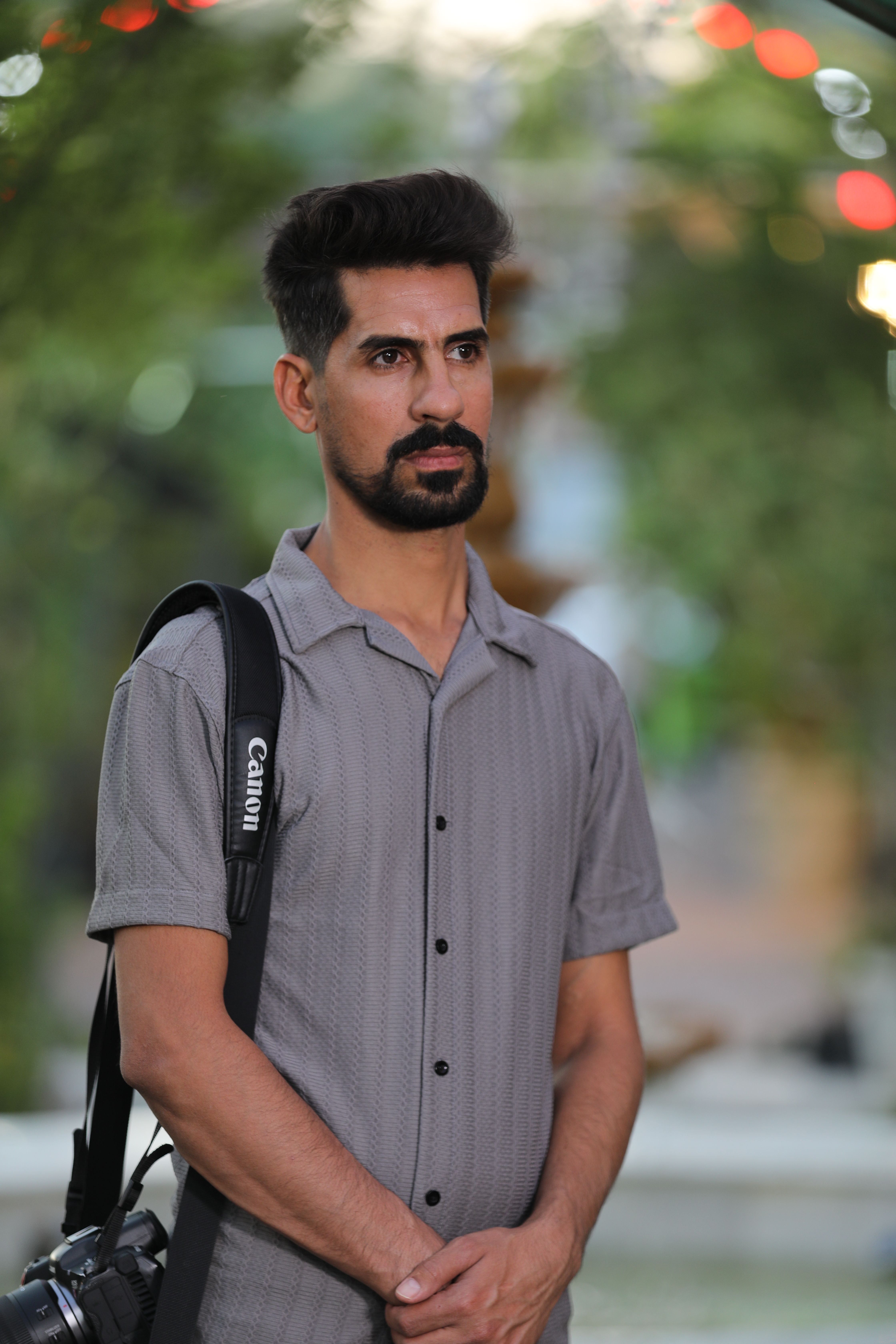A thoughtful photographer holding a camera in a serene outdoor environment.