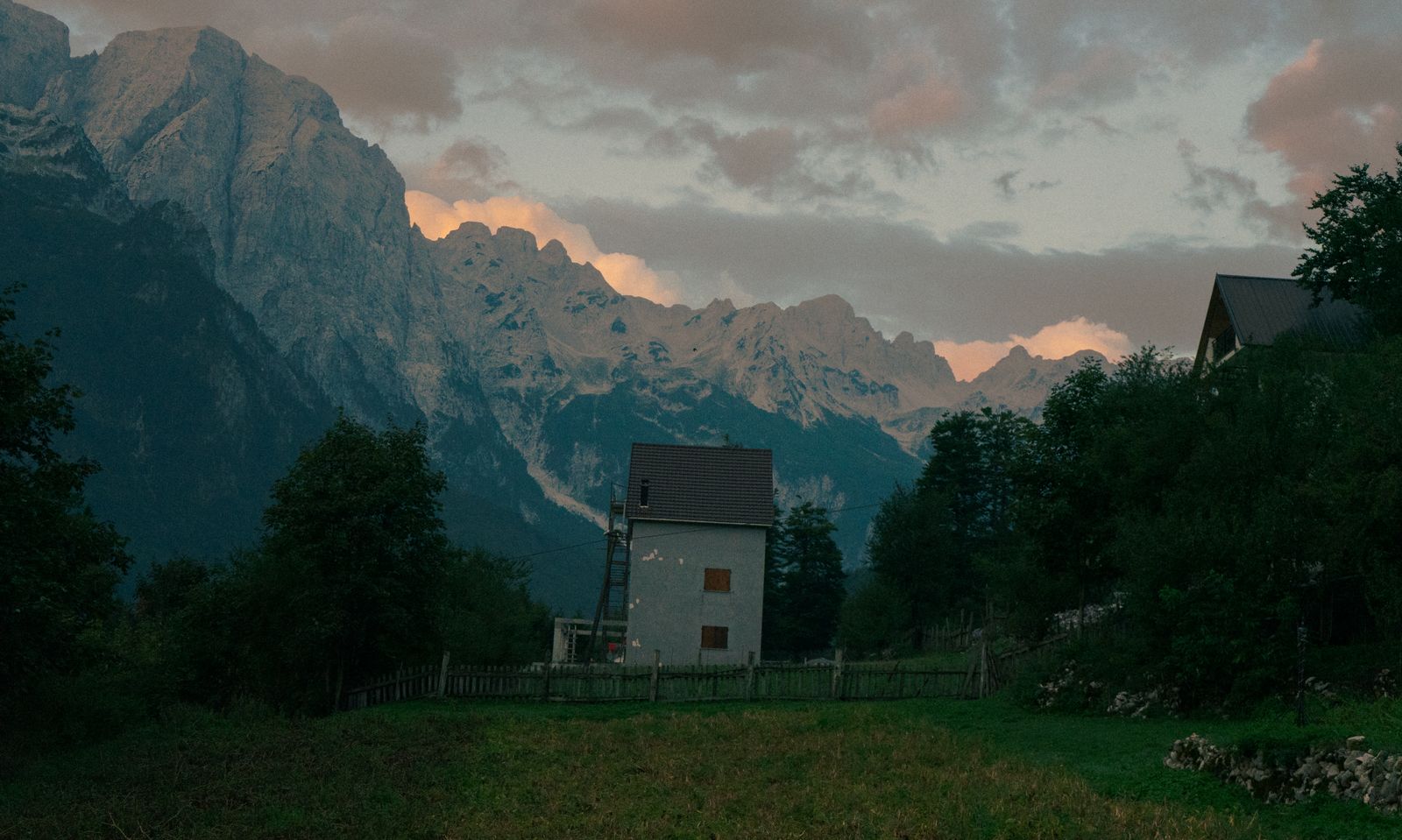Mountain landscape in Valbonë, Albania with peaks and a house at dusk