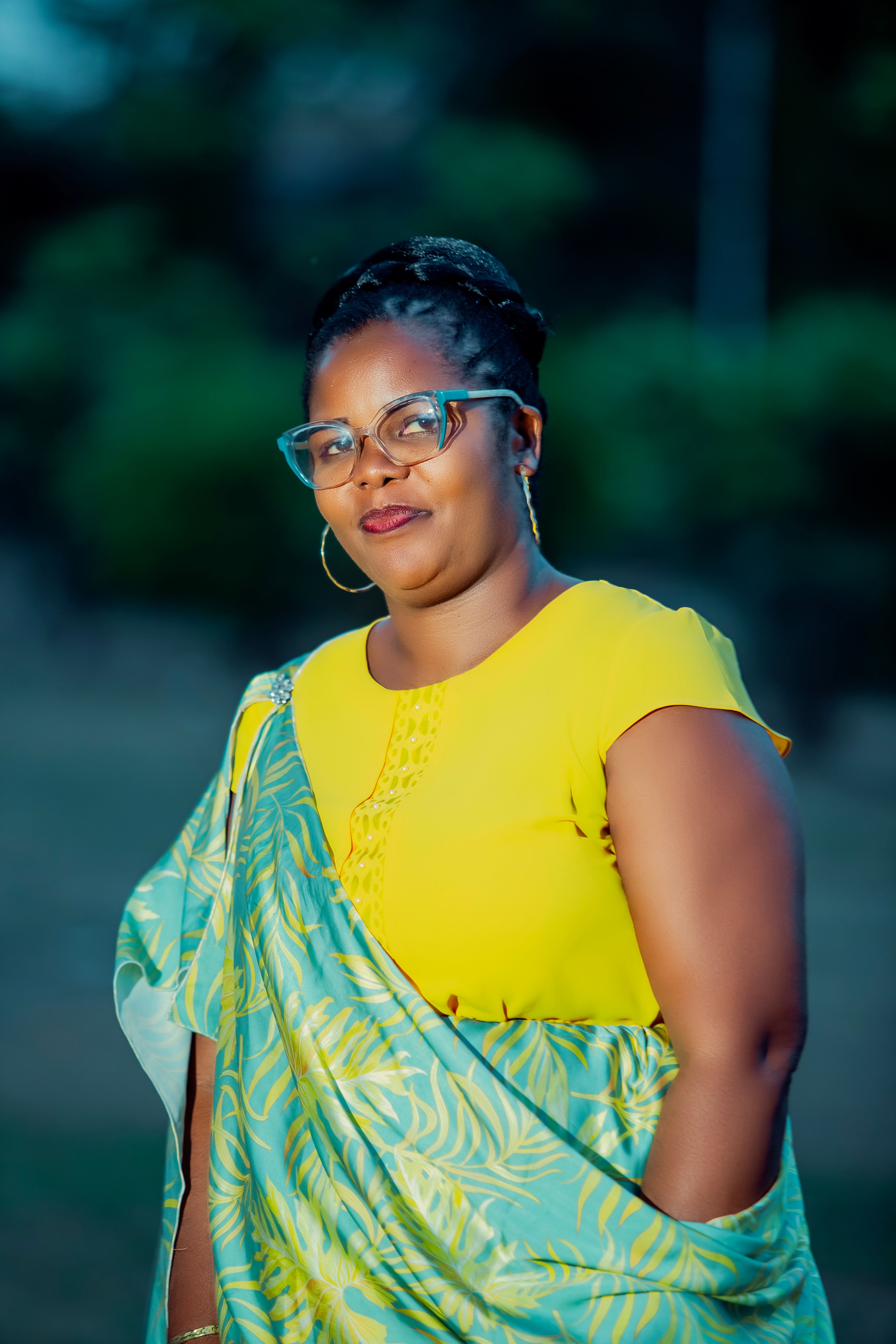 Elegant portrait of a woman wearing glasses and vibrant traditional clothing outdoors.