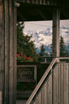 Cozy chalet veranda overlooking snow-capped Alps with a warm welcome sign.