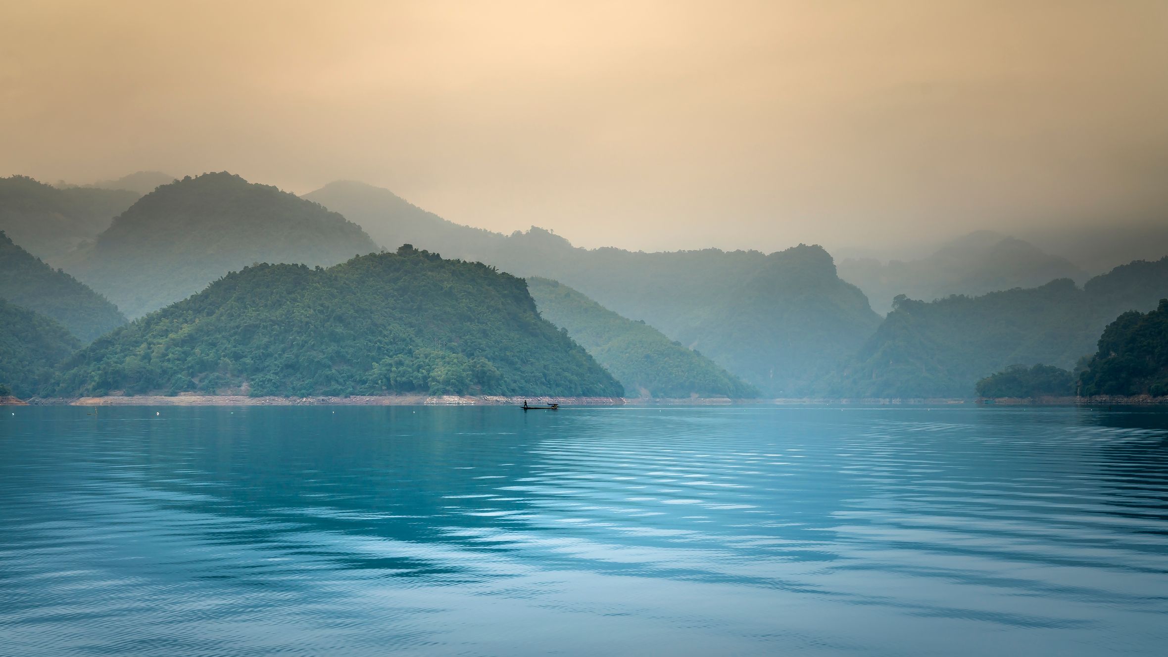 Tranquil scene of a misty lake with mountains reflecting in the calm water.