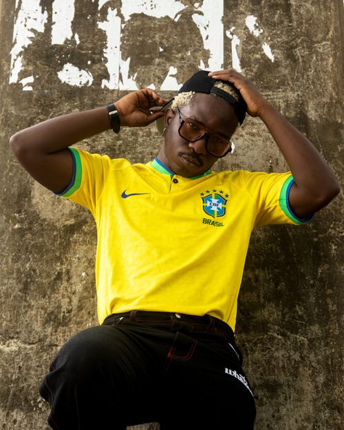 Free Stylish young man wearing a Brazil jersey leaning against a wall. Stock Photo