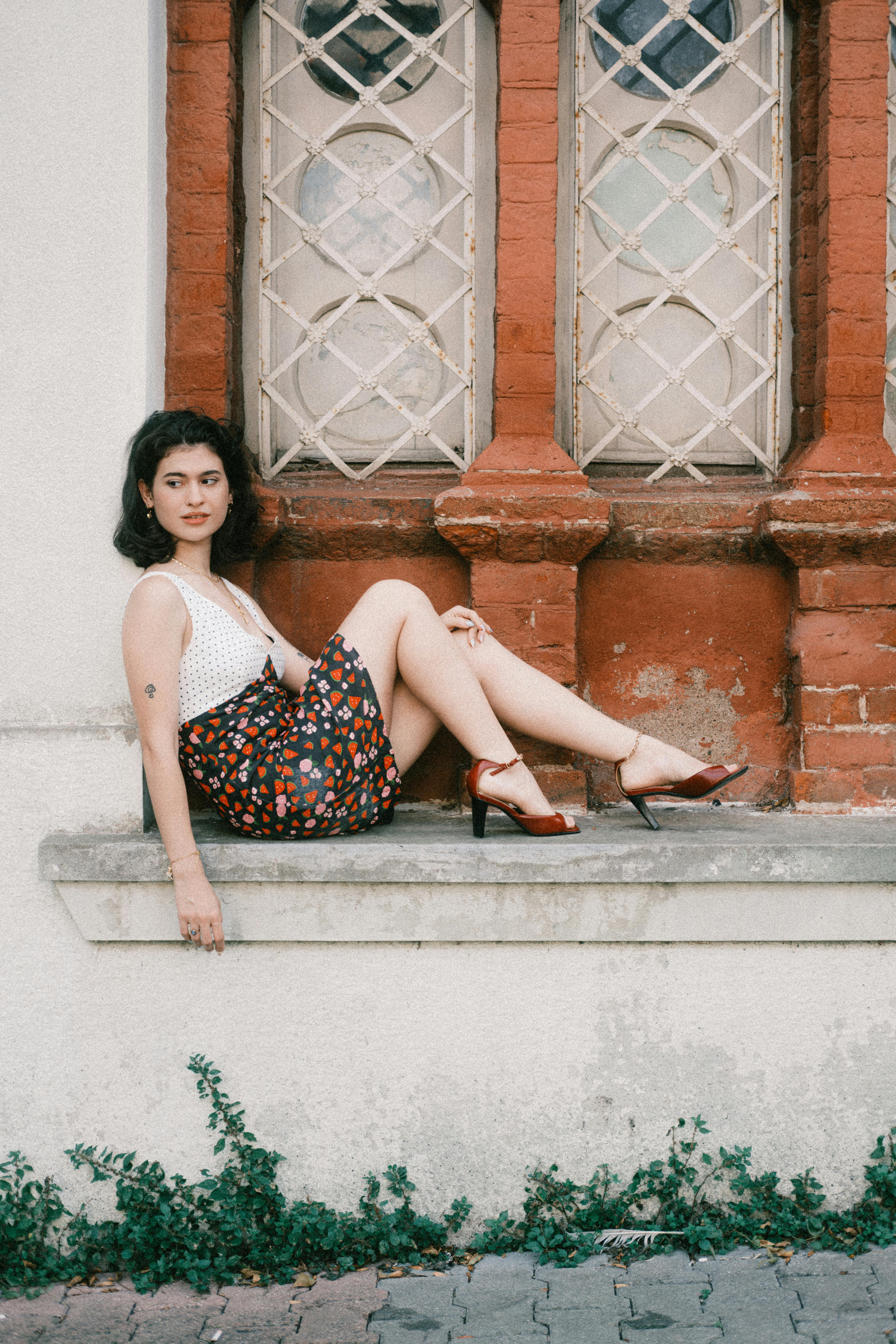 Elegant woman in summer attire sitting by a rustic window
